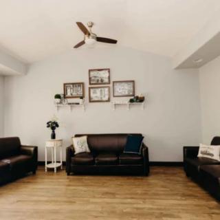 A minimalist living room with dark sofas, wooden flooring, and wall art.
