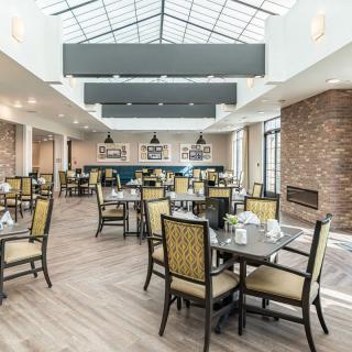 A modern dining area with a skylight ceiling, featuring tables and chairs in a tastefully decorated interior.