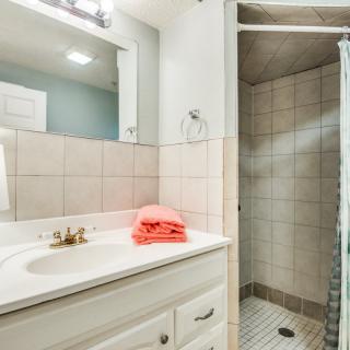 A clean and modern bathroom with a sink, mirror, and shower.