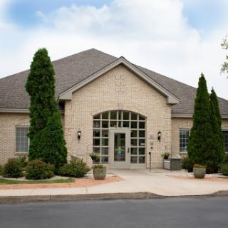 A modern brick building with large glass doors and landscaped surroundings.