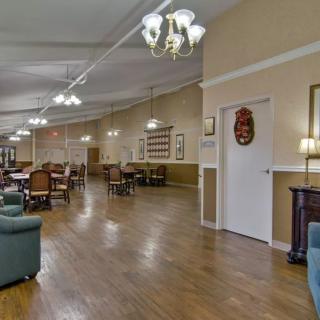 A spacious interior with dining tables and seating, featuring elegant chandeliers and wooden flooring.