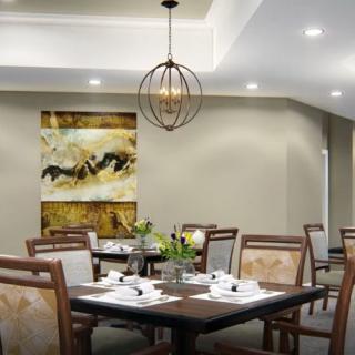 A modern dining room with elegant decor, featuring a chandelier, neatly set tables, and abstract artwork on the wall.
