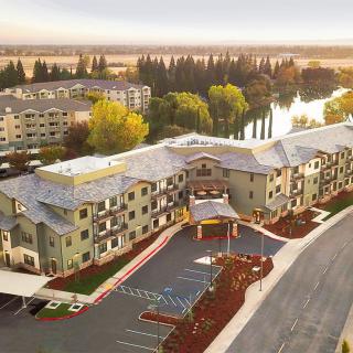 An aerial view of a residential complex surrounded by natural scenery and a nearby water body.