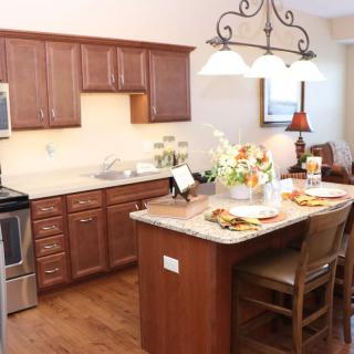 A cozy kitchen with wooden cabinets, an island with seating, and elegant lighting.