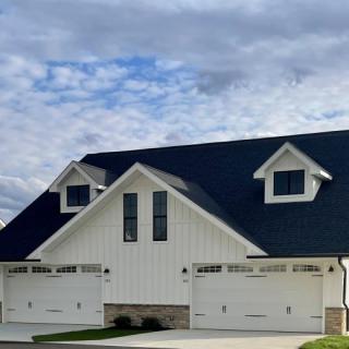 A suburban house with a dark roof and white exterior featuring multiple garages.