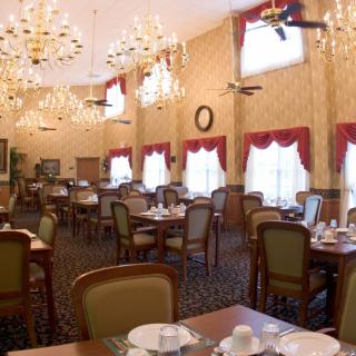 An elegant dining room with chandeliers, arranged tables, and large windows.