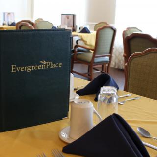 A sophisticated dining setup at Evergreen Place, featuring a neatly arranged table with a menu and napkins.