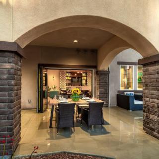 A luxurious outdoor dining area with stone columns and a modern patio setup under an elegant archway.