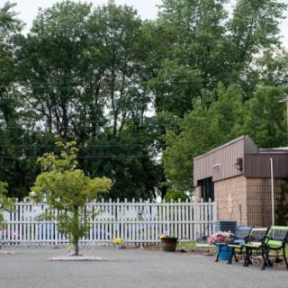 A small outdoor area with benches, surrounded by trees and a white picket fence.