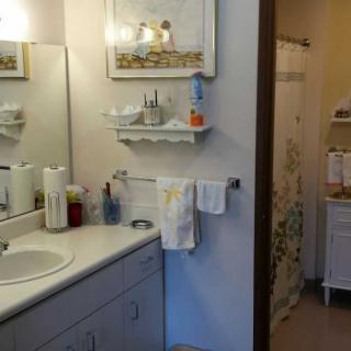 A clean and organized bathroom featuring a sink, mirror, and neatly arranged toiletries on a shelf.