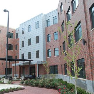 A modern multi-story building with a brick facade and landscaped outdoor area.