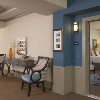 A well-decorated hallway featuring elegant chairs, artwork on the walls, and decorative vases.