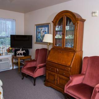 A cozy living room with armchairs, a wooden cabinet, and a television.