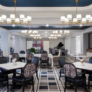 A sophisticated dining area with elegant chandeliers and a grand piano, featuring modern furnishings and stylish decor.
