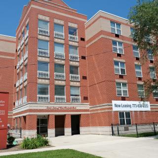 A modern brick apartment building with multiple floors and windows, set in an urban environment.