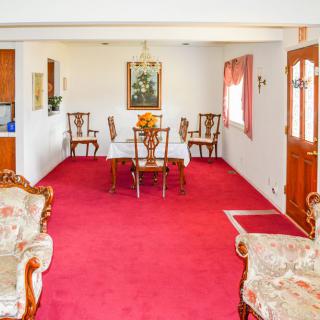 A traditional living and dining space with red carpeting and antique furniture.