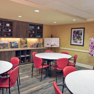 A modern conference room with round tables, red chairs, and bookshelves.