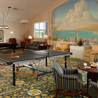 A cozy game room featuring a ping pong table, billiards, and a seating area with a large mural on the wall.