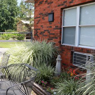 A cozy outdoor seating area with plants and a brick wall backdrop.
