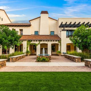 A beautiful Mediterranean-style house with a well-maintained garden and central fountain.