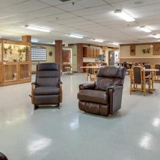 A spacious community room with recliner chairs and tables, offering a comfortable seating area.