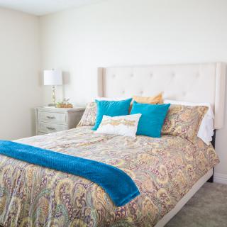 A cozy bedroom with colorful bedding and decorative pillows.