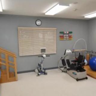 A physical therapy room equipped with various exercise machines and a staircase for rehabilitation exercises.