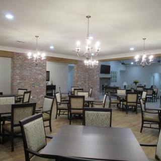 An empty dining area with neatly arranged tables, chairs, and decorative chandeliers.