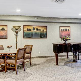 A cozy room with a grand piano, artwork on the walls, and comfortable seating.