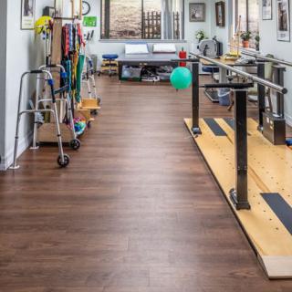 A physical therapy room equipped with parallel bars and various rehabilitation tools.