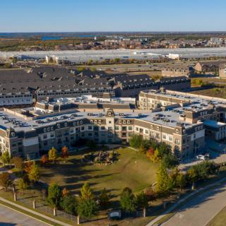 Aerial view of a residential complex with surrounding green spaces and a suburban landscape.
