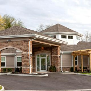 A modern building with stone and siding exterior, featuring a covered entrance.