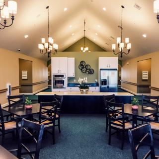 A modern dining area with a central kitchen and stylish chandeliers.