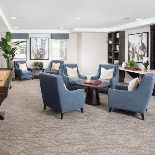 A modern lounge area with blue upholstered chairs and a central table, featuring stylish decor and artwork on the walls.