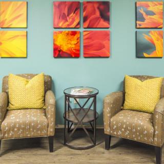 A cozy living room setup featuring two patterned armchairs with yellow pillows, a small round table between them, and colorful abstract artwork on the wall.