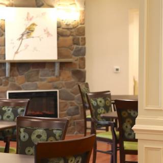 A cozy dining area with patterned chairs and a stone fireplace.