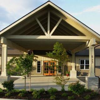 A modern building entrance with a covered walkway and landscaped surroundings.