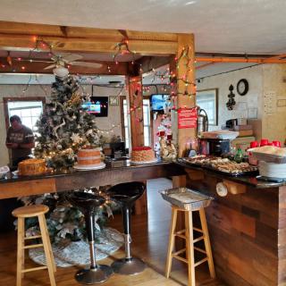 A cozy cafe interior decorated for the holidays with a Christmas tree and festive ornaments.