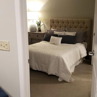 A cozy bedroom with a neatly made bed, nightstand, and lamp.