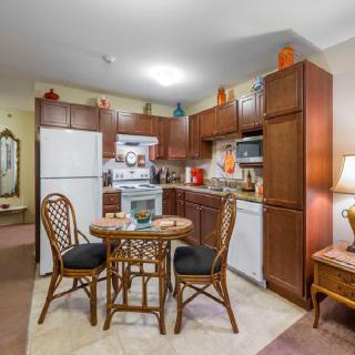 A cozy kitchen and dining area with wooden cabinets, a small round table, and wicker chairs.