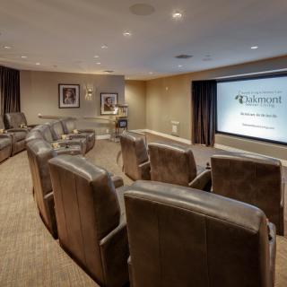 A cozy home theater room with recliner seating and a large projector screen.