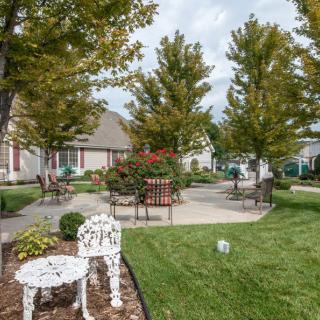 A serene garden with trees, outdoor seating, and a well-maintained lawn in a residential area.