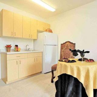 A small kitchen area with wooden cabinets, a white refrigerator, and a table set with a decorative centerpiece.