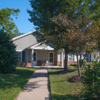 A suburban house with a garden and pathway under a clear blue sky.