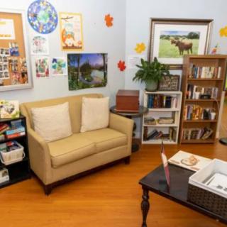 A cozy living room with a comfortable sofa, bookshelf filled with books, and various decorations and artworks on the walls.