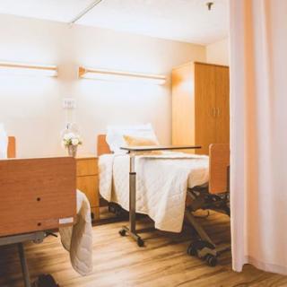 A clean and well-organized hospital room with two beds separated by a curtain.