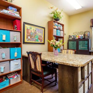 A well-organized office space with a large desk, decorative shelves, and vibrant artwork.