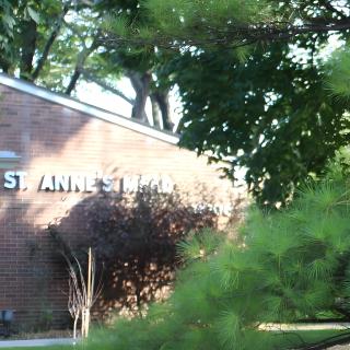 A brick building partially obscured by trees and greenery.