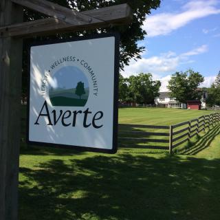 Sign for Averte, located in a grassy area with trees and a wooden fence.