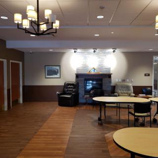 A spacious lobby area featuring tables, chairs, and a cozy fireplace.